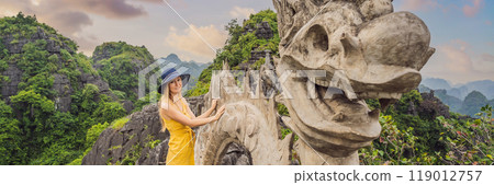 BANNER, LONG FORMAT Woman tourist on background of amazing huge dragon statue at limestone mountain top near Hang Mua view point at foggy morning. Popular tourist attraction at Tam Coc, Ninh Binh 119012757