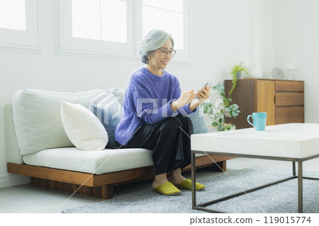 一位身穿針織品的高級女性在客廳放鬆 119015774