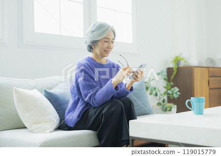 一位身穿針織品的高級女性在客廳放鬆 一位身穿針織品的高級女性在客廳放鬆 119015779