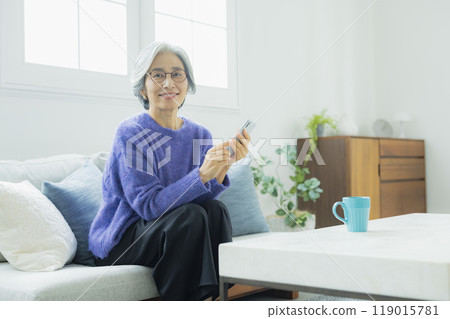 一位身穿針織品的高級女性在客廳放鬆 119015781