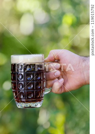 closeup male hand with mug of dark beer closeup male hand with mug of dark beer 119015792