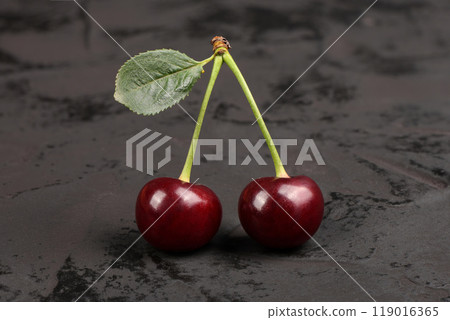 Fresh red cherries with green leaves isolated on black background. Natural background. Fresh red cherries with green leaves isolated on black background. Natural background. 119016365