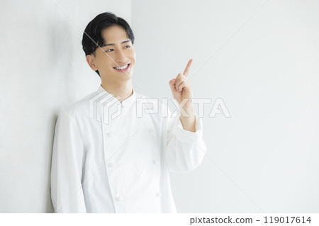 A young man wearing a chef's coat 119017614