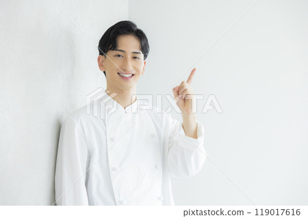 A young man wearing a chef's coat A young man wearing a chef's coat 119017616
