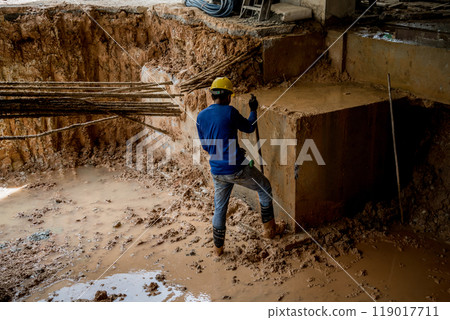 Builders in hard hats and blue jackets work at a construction site Builders in hard hats and blue jackets work at a construction site 119017711