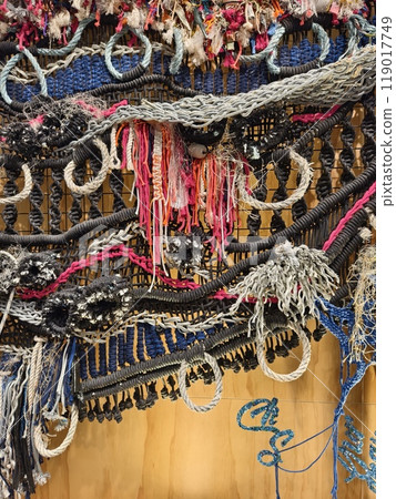 A ropes piece of art is displayed on a wooden wall A ropes piece of art is displayed on a wooden wall 119017749