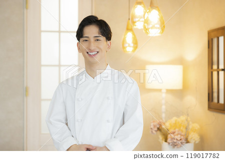 A young man wearing a chef's coat 119017782