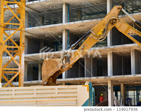 Excavator loads ground into a dump truck at a construction site 119017936
