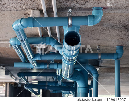 A bright blue pipes attached to a solid concrete wall 119017937