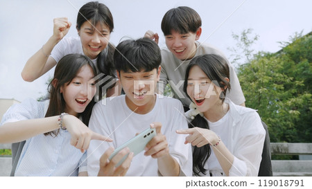 Happy young group of friends using phone and smiling together outdoor. 119018791