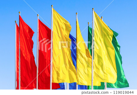 Colorful flags fluttering against a blue sky 119019844