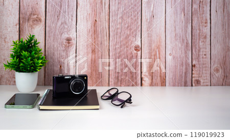 Mock up modern home decor with camera, Houseplant, Phone, Notebook, Glasses. Artist workspace with copy space for products display montage. 119019923