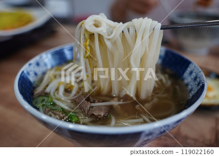 Vietnamese rice noodles in a bowl with chopsticks on a wooden table Vietnamese rice noodles in a bowl with chopsticks on a wooden table 119022160