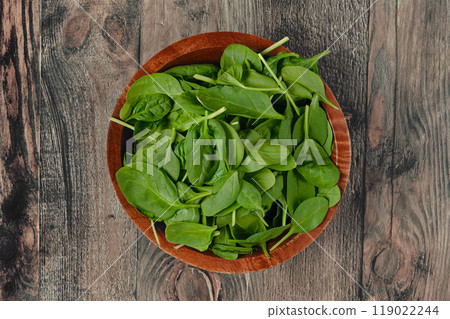 Fresh crisp spinach leaves in a wooden bowl on a rustic wooden table ready for cooking or salads Fresh crisp spinach leaves in a wooden bowl on a rustic wooden table ready for cooking or salads 119022244