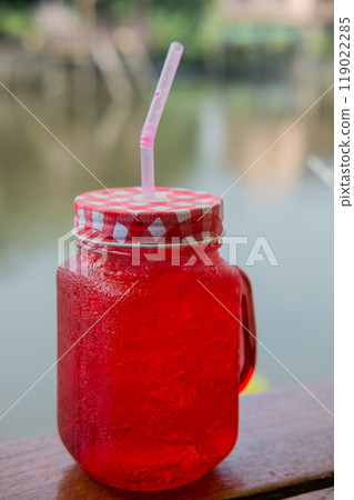red drink juice on wooden table with riverside view 119022285