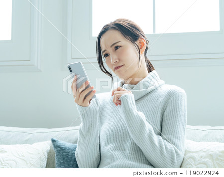 A woman troubled while watching a smartphone 119022924