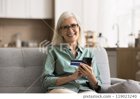 Portrait of happy older woman holding smartphone and credit card Portrait of happy older woman holding smartphone and credit card 119023240