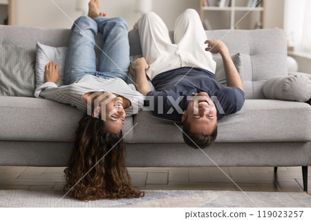 Cheerful cute young couple relaxing on grey soft couch Cheerful cute young couple relaxing on grey soft couch 119023257