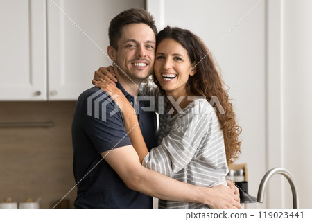 Cheerful young couple hugging with faces touch in kitchen 119023441