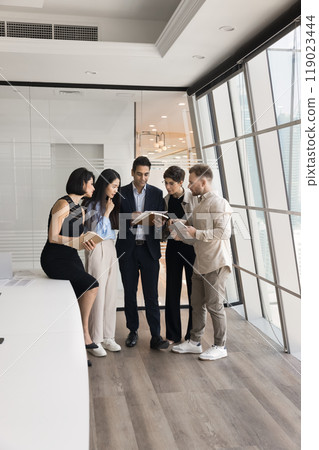 Indian business leader and team of managers reading legal document Indian business leader and team of managers reading legal document 119023444