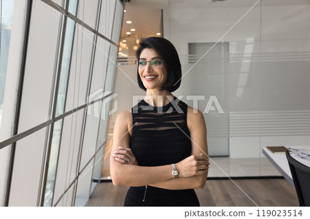 Positive confident young business leader woman standing with hands folded 119023514