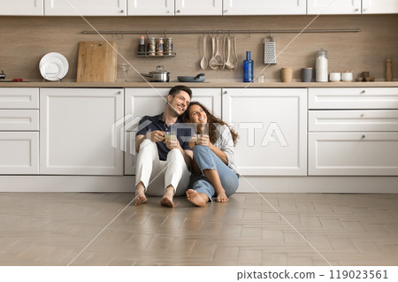 Happy couple of homeowners sitting on floor close together Happy couple of homeowners sitting on floor close together 119023561