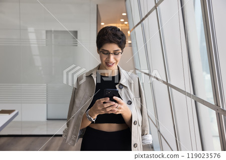 Positive entrepreneur woman in casual typing on mobile phone 119023576