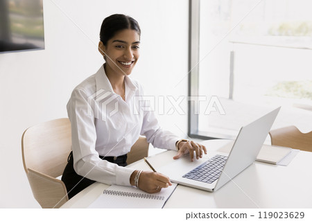 Young Indian businesswoman work online using laptop take notes Young Indian businesswoman work online using laptop take notes 119023629