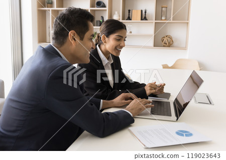 Diverse Indian persons coworkers cooperate prepare document report on laptop Diverse Indian persons coworkers cooperate prepare document report on laptop 119023643