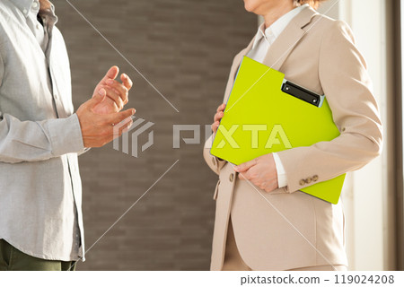 A middle-aged female real estate salesperson showing an apartment to a male customer 119024208