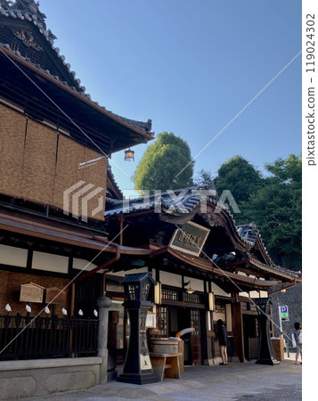 Dogo Onsen in the morning and a tourist woman purchasing a bathing ticket Dogo Onsen in the morning and a tourist woman purchasing a bathing ticket 119024302
