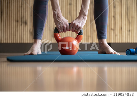 Closeup view of a woman holding kettlebell weight for deadlift exercise 119024858