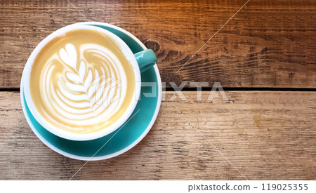 Coffee cup on a wooden table, top view, hot drink with foam in a rustic cafe setting. Brown beverage Coffee cup on a wooden table, top view, hot drink with foam in a rustic cafe setting. Brown beverage 119025355