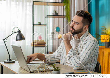 Freelancer man prepares startup project for presentation finds idea using laptop at home office Freelancer man prepares startup project for presentation finds idea using laptop at home office 119027295