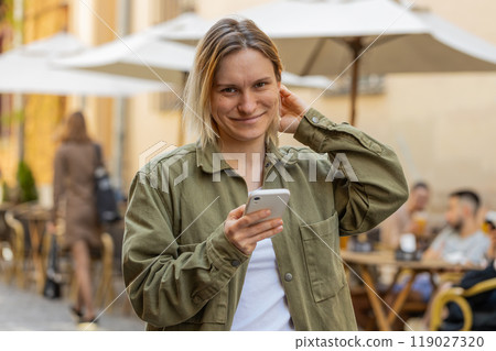 Woman using smartphone texting social media messages looking for a way on navigator map city street Woman using smartphone texting social media messages looking for a way on navigator map city street 119027320