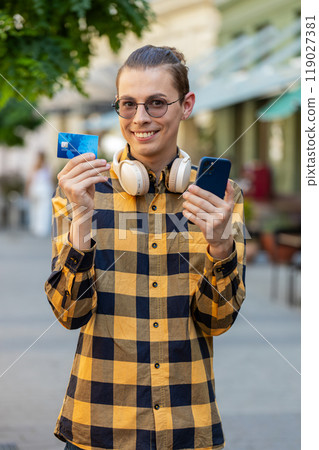Man using credit bank card smartphone while transferring money, purchases online shopping outdoors Man using credit bank card smartphone while transferring money, purchases online shopping outdoors 119027381