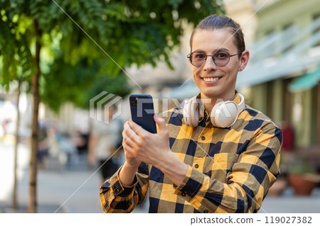 Happy young man tourist using smartphone internet social media web app chatting on urban city street Happy young man tourist using smartphone internet social media web app chatting on urban city street 119027382