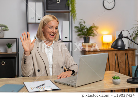 Mature businesswoman using laptop talking on online communication video call at home office desk Mature businesswoman using laptop talking on online communication video call at home office desk 119027424