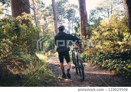 Nature, fitness and man cyclist with a bicycle for cardio training, health or wellness in the woods. Sports, cycle and male athlete walking with a bike outdoor in the forest to practice for a race. 119029506
