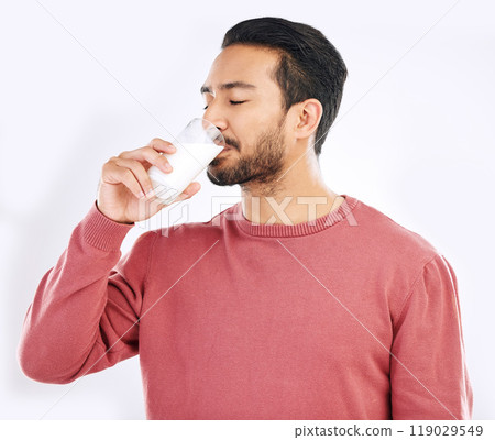 Man drinking glass of milk in studio, white background and backdrop for healthy dairy, smoothies and diet. Male model, cup and calcium of smoothie, vanilla milkshake and nutrition of protein drink 119029549