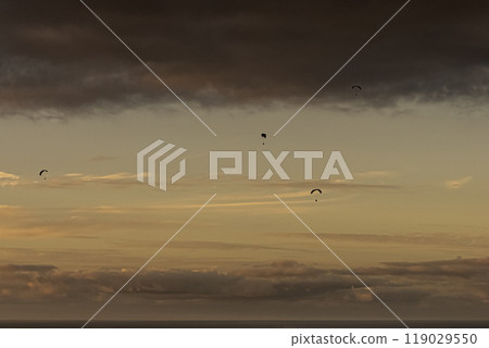 three sport kites floating over the sea on the horizon 119029550