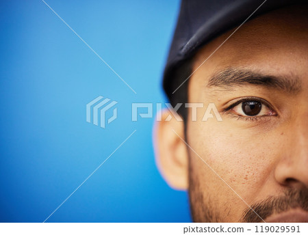 Eye, closeup and portrait of half of man in sports on blue background with advertising, mockup or space with athlete in studio. Serious, face and Indian person in cricket or baseball cap and fitness Eye, closeup and portrait of half of man in sports on blue background with advertising, mockup or space with athlete in studio. Serious, face and Indian person in cricket or baseball cap and fitness 119029591