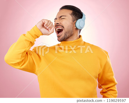 Asian man, headphones and listening to music for karaoke or singing against a pink studio background. Happy male person enjoying online audio streaming, sound track or songs with headset on mockup 119029597