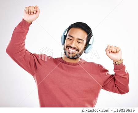 Headphones, happy and man dancing in a studio to music, playlist or album for entertainment. Happiness, dance and Indian male model moving to the radio or streaming a song by a white background. Headphones, happy and man dancing in a studio to music, playlist or album for entertainment. Happiness, dance and Indian male model moving to the radio or streaming a song by a white background. 119029639