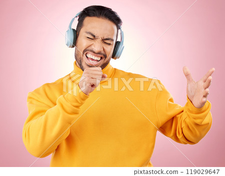 Asian man, headphones and listening to music while singing for karaoke against a pink studio background. Happy male person enjoying online audio streaming, sound track or songs with headset on mockup Asian man, headphones and listening to music while singing for karaoke against a pink studio background. Happy male person enjoying online audio streaming, sound track or songs with headset on mockup 119029647
