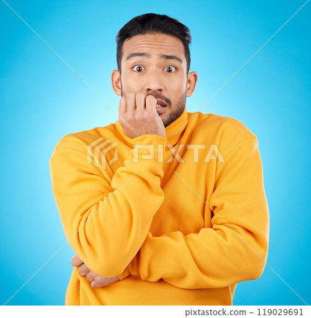 Anxiety, portrait and asian man biting nails in studio with stress, suspense or crisis on blue background. Face, worry and nervous male with emoji reaction to news, gossip or did you know drama 119029691