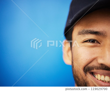 Studio, portrait and closeup on half of man in sports on blue background with advertising, mockup or space with athlete. Happy, face and smile with cricket or baseball cap and fitness or wellness 119029700