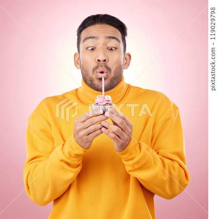 Food, cupcake and man blowing candle in studio for celebration, party and dessert. Birthday, wish and flame with face of male person and cake on pink background for surprise, candy and gift mockup Food, cupcake and man blowing candle in studio for celebration, party and dessert. Birthday, wish and flame with face of male person and cake on pink background for surprise, candy and gift mockup 119029798