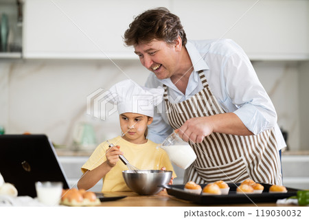 Father and daughter preparing muffins in kitchen Father and daughter preparing muffins in kitchen 119030032