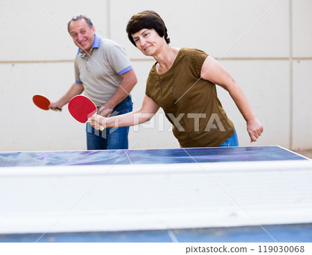 Mature man and woman playing table tennis Mature man and woman playing table tennis 119030068